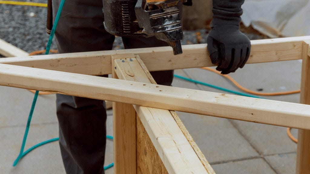 Close-up of a nail gun securing timber deck framing joists