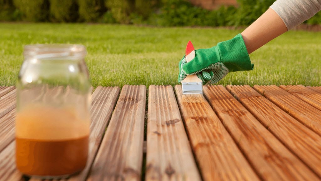 Applying protective stain to timber decking boards with a brush