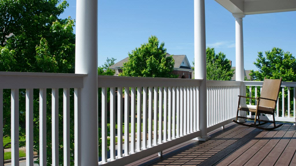 Timber deck beside a white balustrade on a covered verandah with a rocking chair