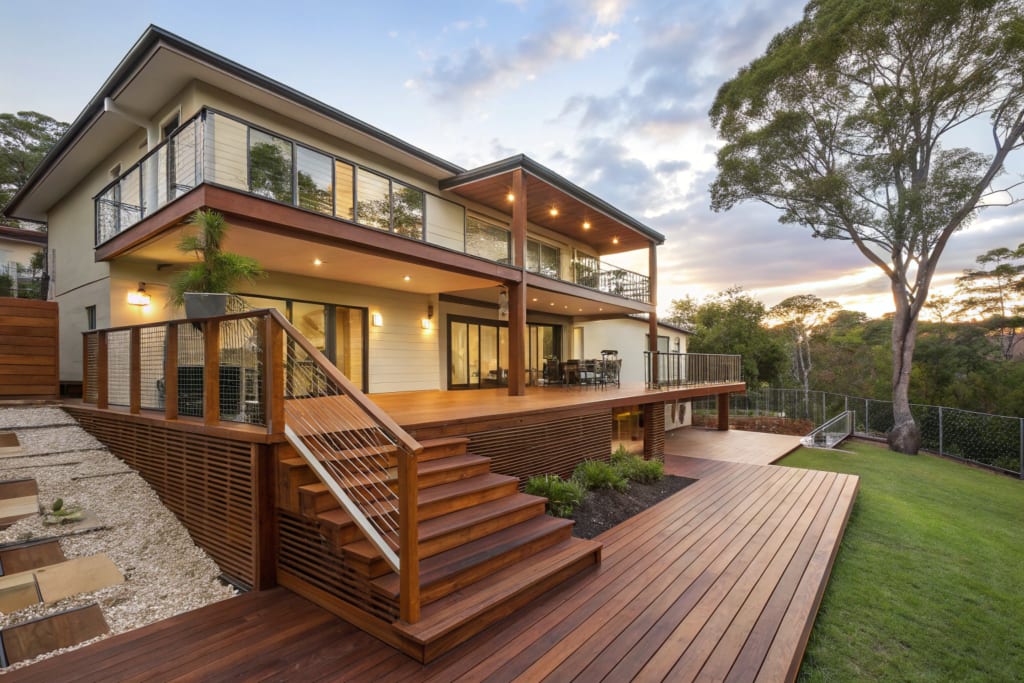 Two-level elevated timber deck with a staircase down to the backyard at dusk